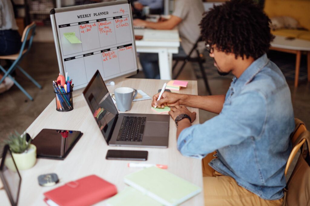 Développeur web prenant des notes en travaillant, avec un planning. 